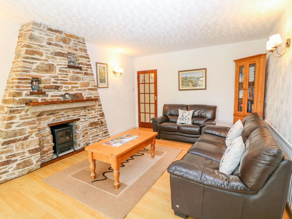 A living room with a stone fireplace and leather sofas at Maple Cottage Tavistock