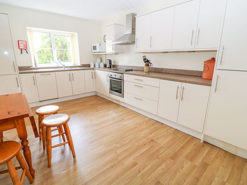 A kitchen with a table and stools at Maple Cottage Tavistock
