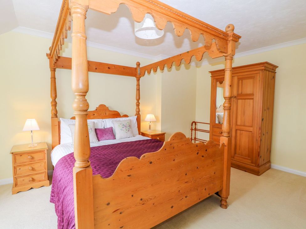 A bedroom with a four-poster bed and wardrobe at Maple Cottage in Tavistock