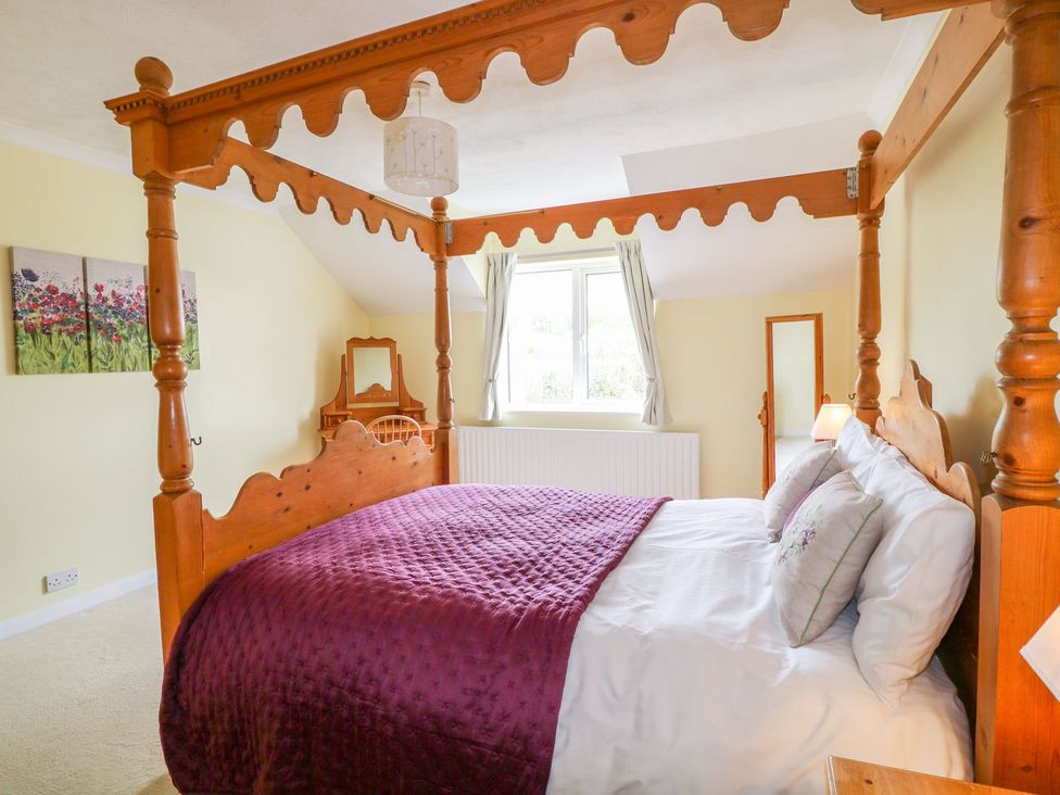 A bedroom with a four poster bed and a window at Maple Cottage Tavistock