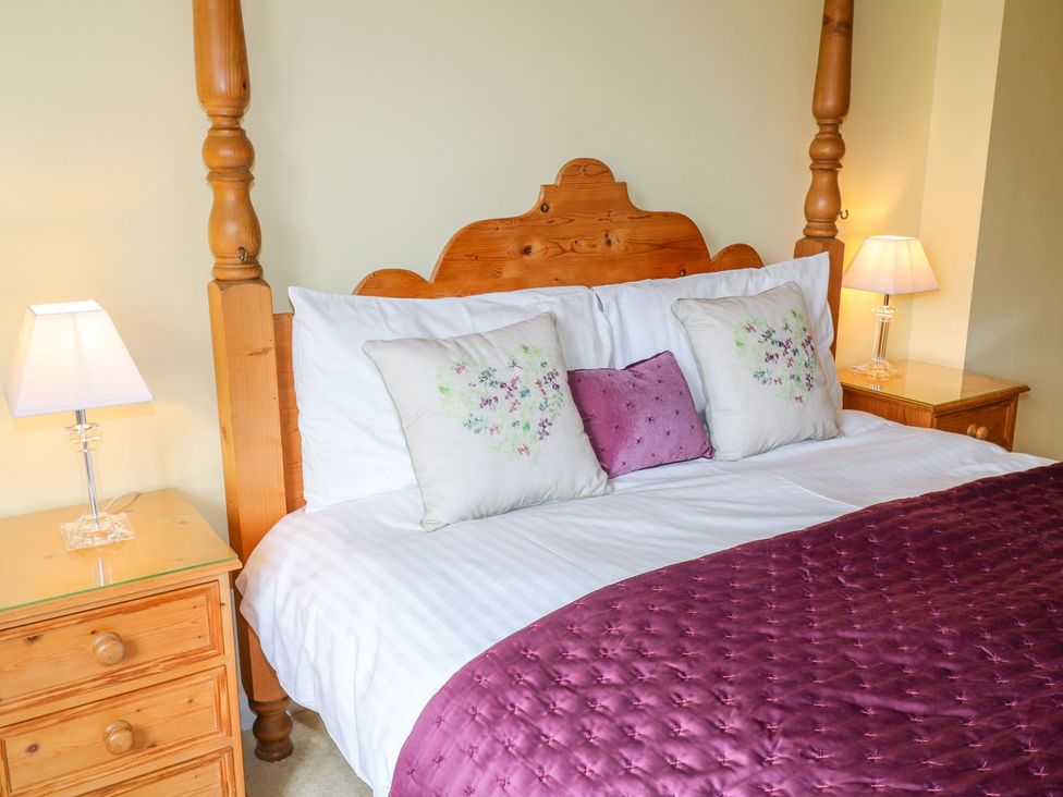 A bedroom with a wooden bed and nightstands at Maple Cottage in Tavistock