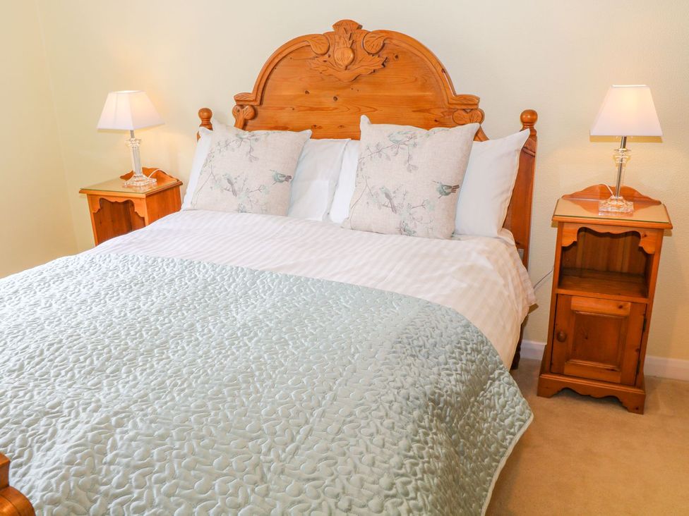 A bedroom with a wooden bed and nightstands at Maple Cottage in Tavistock