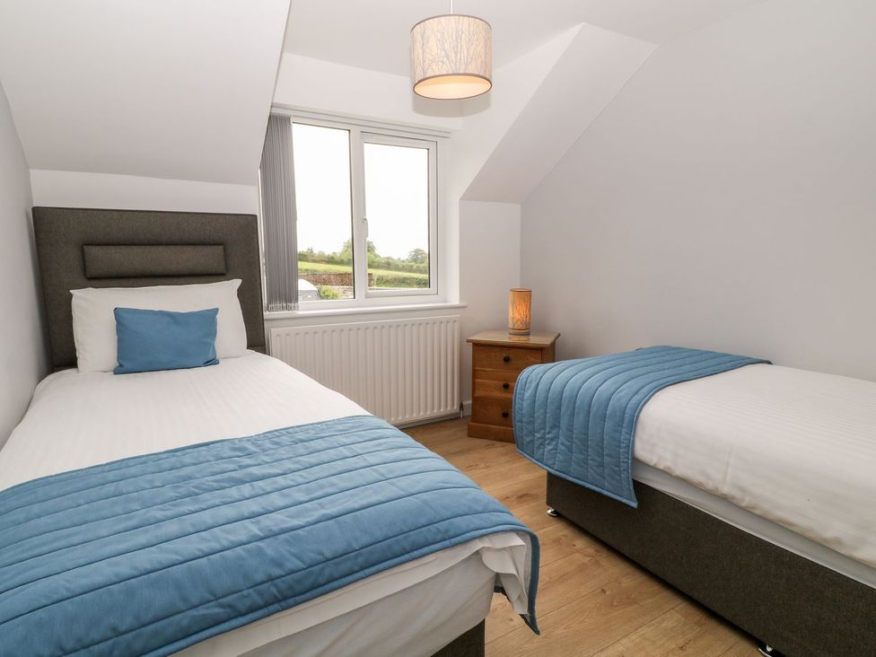 A bedroom with two single beds and a window at Honeysuckle in Tavistock