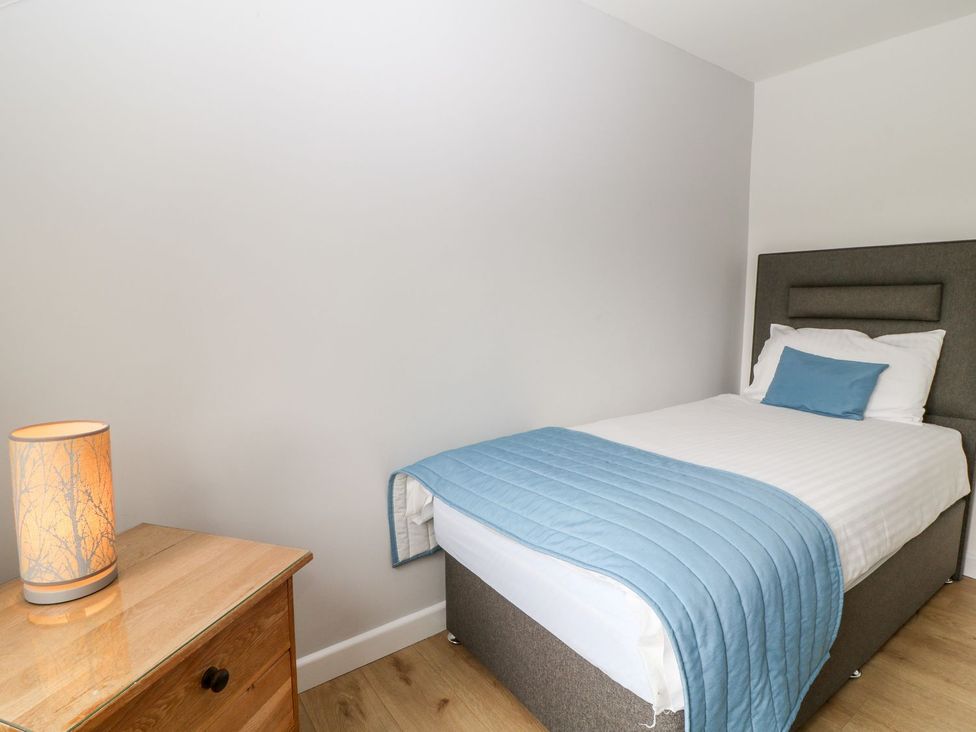 A bedroom with a bed and lamp at Honeysuckle in Tavistock