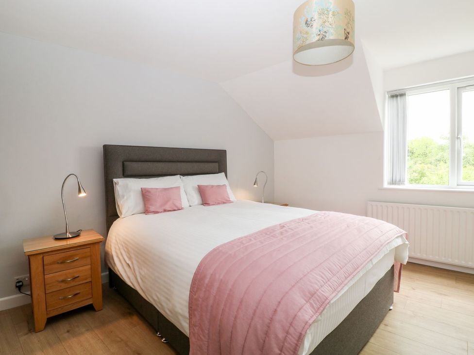A bedroom with a bed and bedside table at Honeysuckle in Tavistock