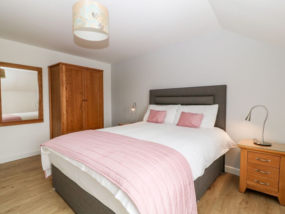 A bedroom with a bed and wardrobe at Honeysuckle in Tavistock