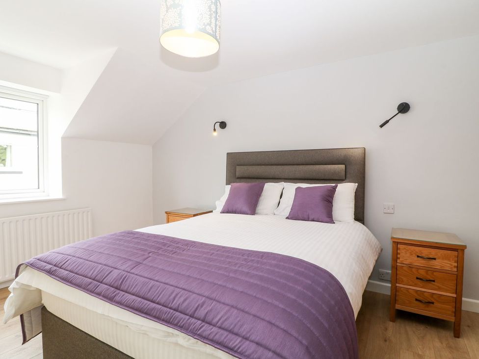 A bedroom with a bed and side tables at Honeysuckle in Tavistock
