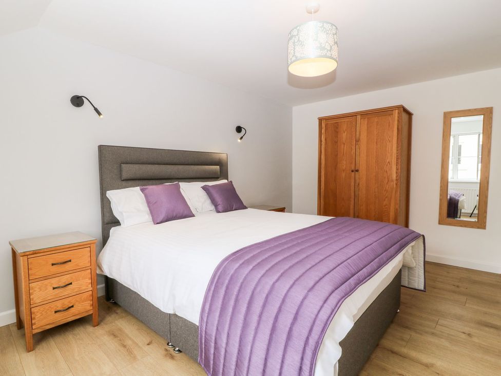 A bedroom with a bed and wardrobe at Honeysuckle in Tavistock
