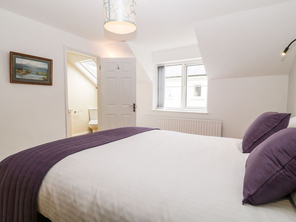 A bedroom with a bed and window at Honeysuckle in Tavistock
