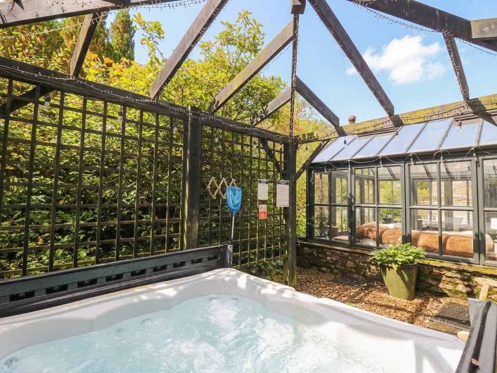 An outdoor area with a hot tub and a greenhouse at Three Mile House in Carnforth