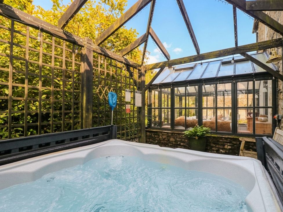 An outdoor area with a hot tub and glass conservatory at Three Mile House Carnforth