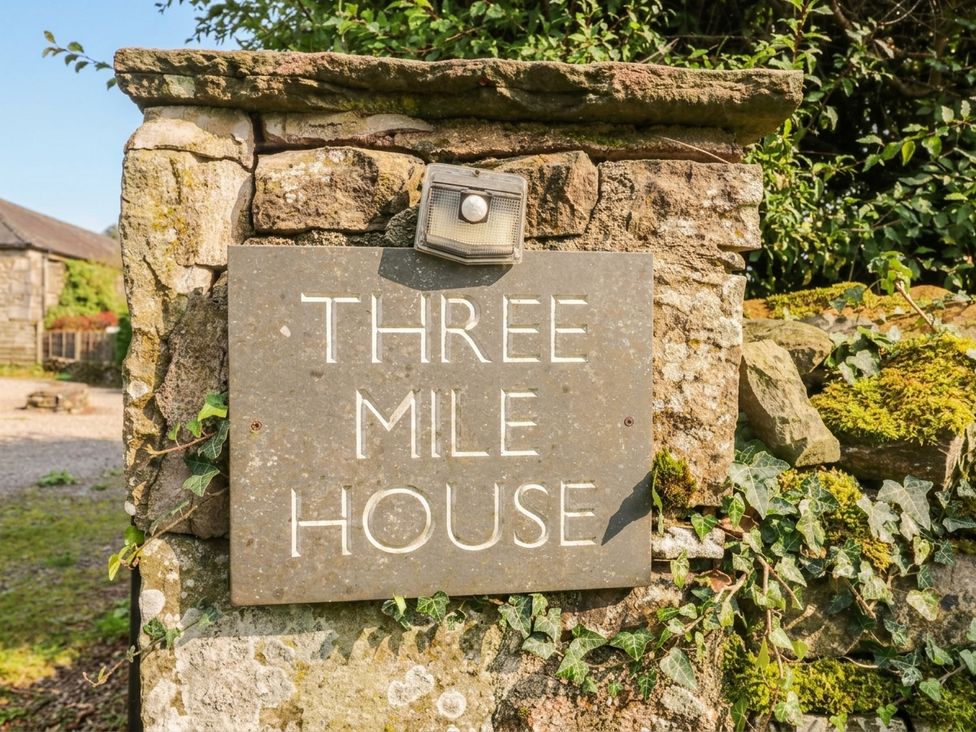 A house sign on a stone wall at Three Mile House in Carnforth
