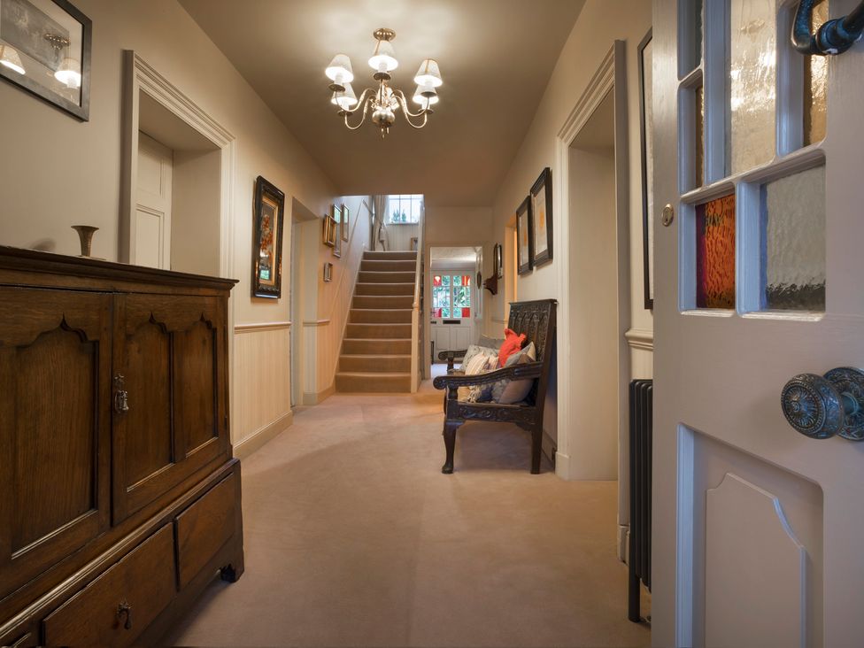 A hallway with a staircase and a chair at Three Mile House in Carnforth