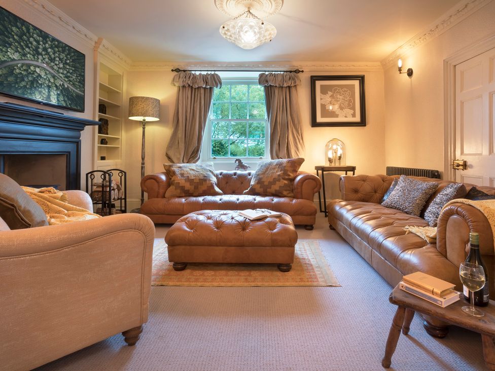 A living room with brown leather sofas and a coffee table at Three Mile House in Carnforth