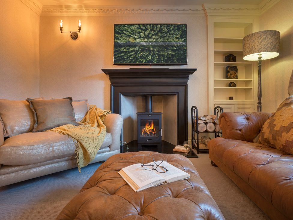 A living room with a fireplace and two sofas at Three Mile House in Carnforth