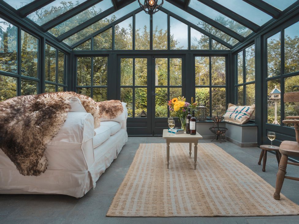 A conservatory with a sofa and side table at Three Mile House in Carnforth