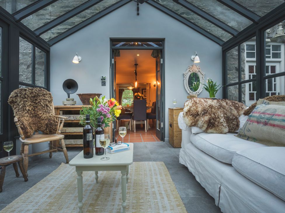 A conservatory with a sofa and coffee table at Three Mile House in Carnforth