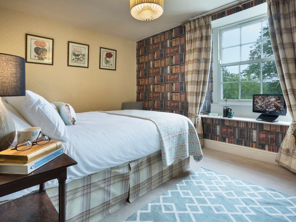 A bedroom with a bed, lamp, and television at Three Mile House in Carnforth