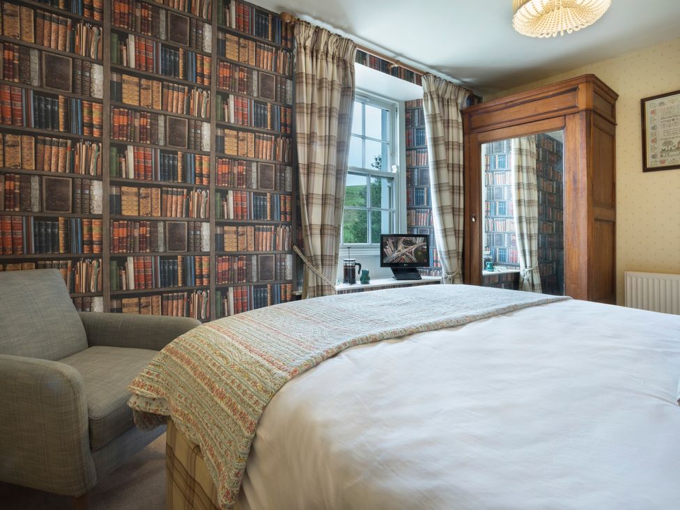 A bedroom with a bed and armchair at Three Mile House in Carnforth