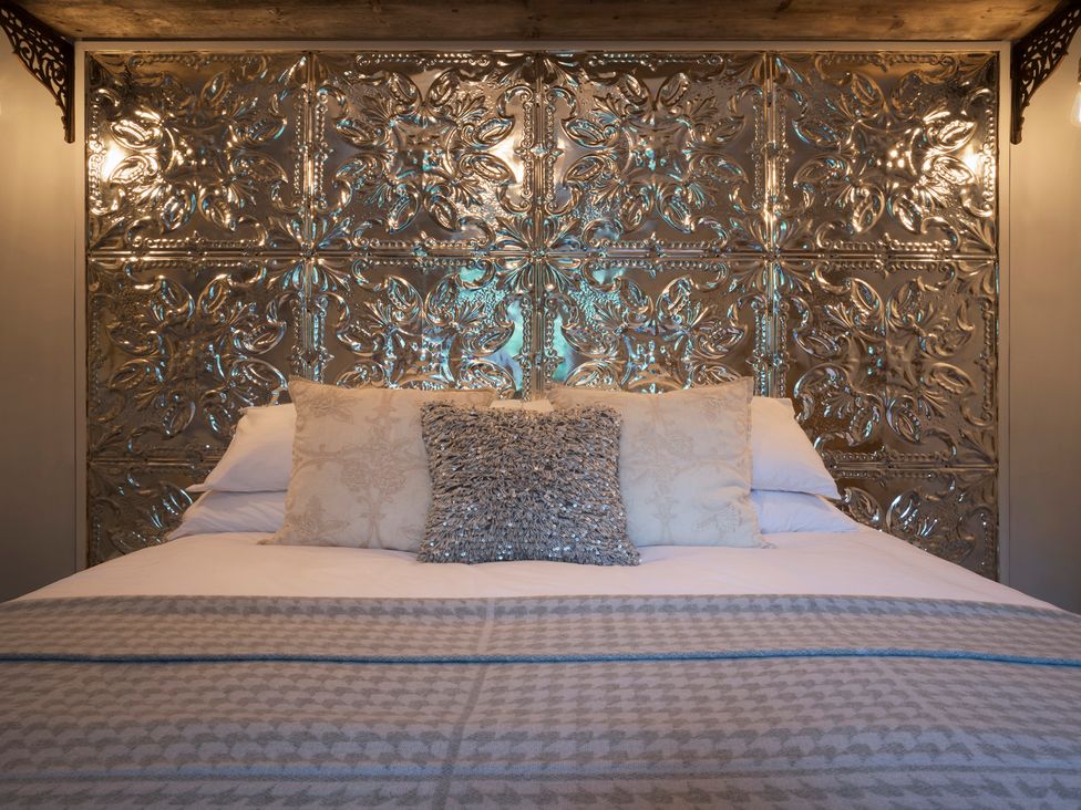 A bed with decorative pillows and a metal headboard at Three Mile House in Carnforth