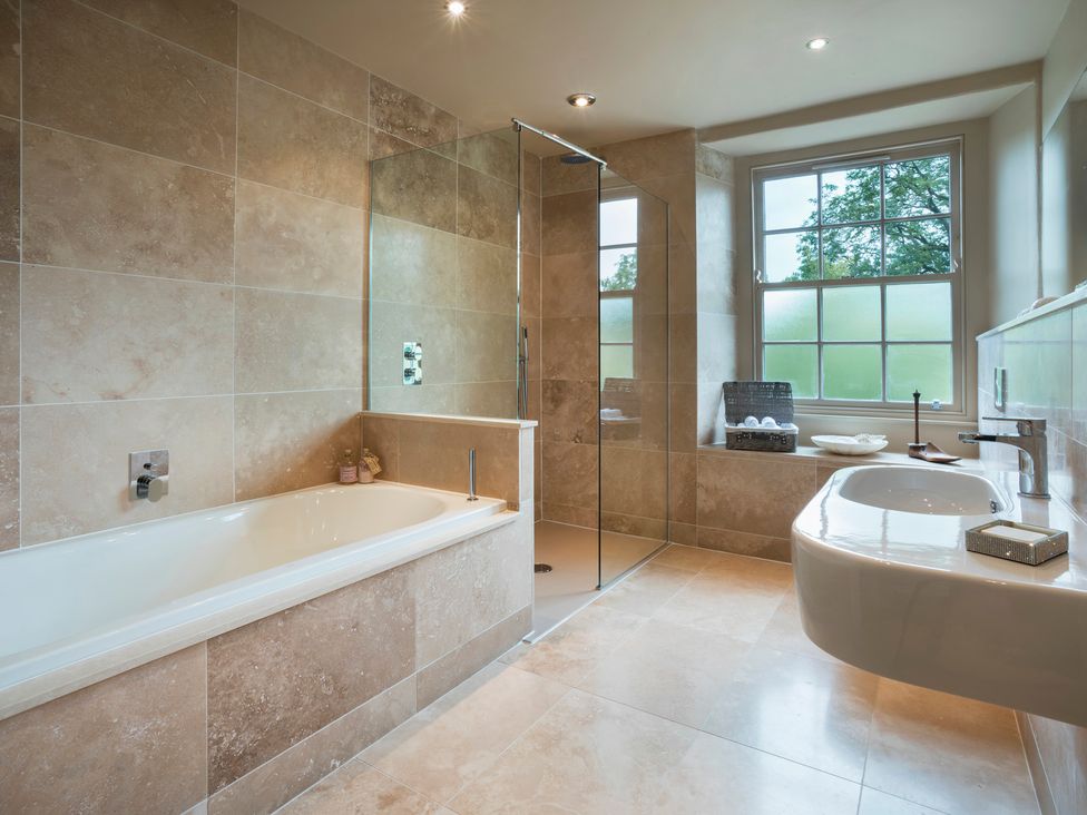 A bathroom with a bathtub, shower, and sink at Three Mile House in Carnforth