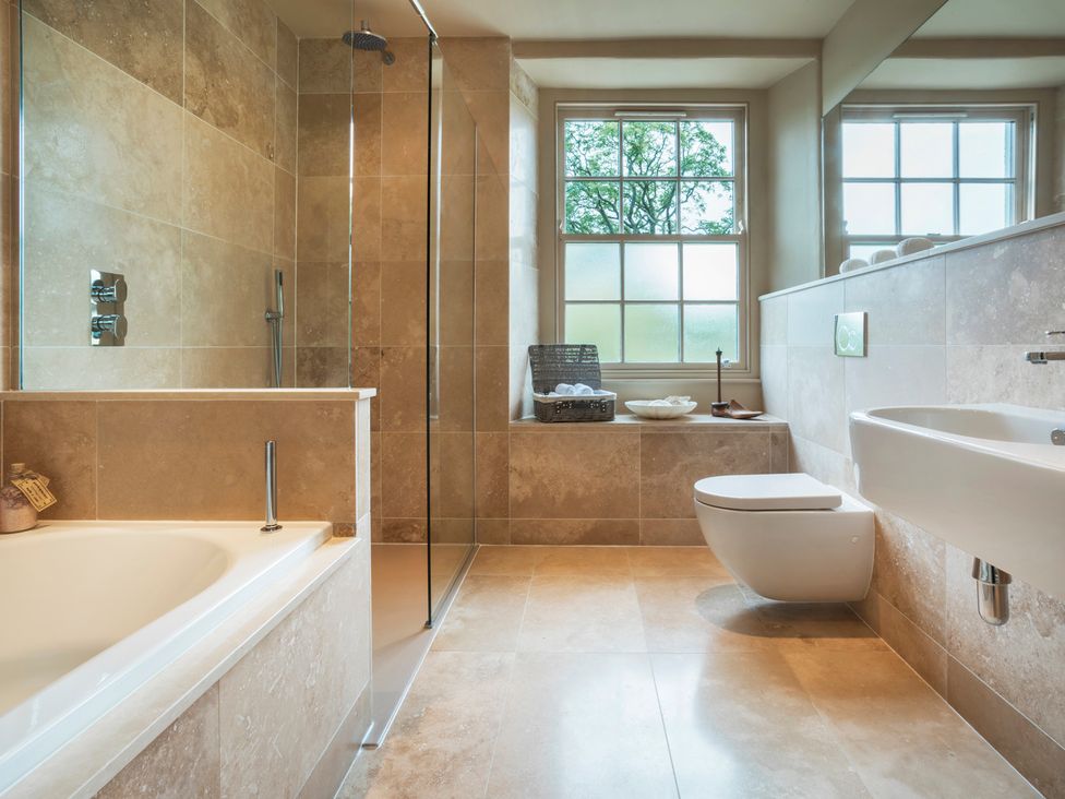 A bathroom with a bathtub, shower, toilet and sink at Three Mile House in Carnforth