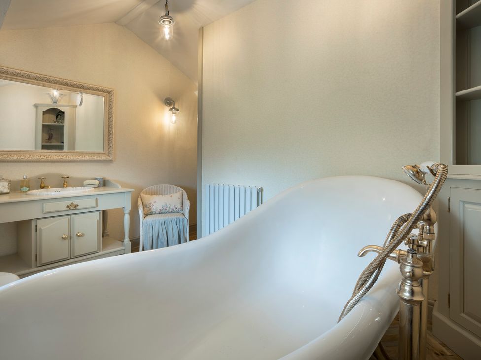 A bathroom with a bathtub, a mirror, and a vanity at Three Mile House in Carnforth