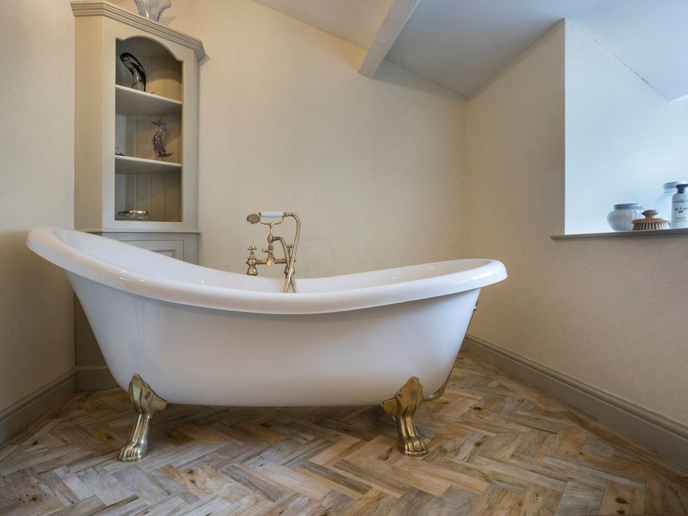 A bathroom with a bathtub and shelves at Three Mile House in Carnforth