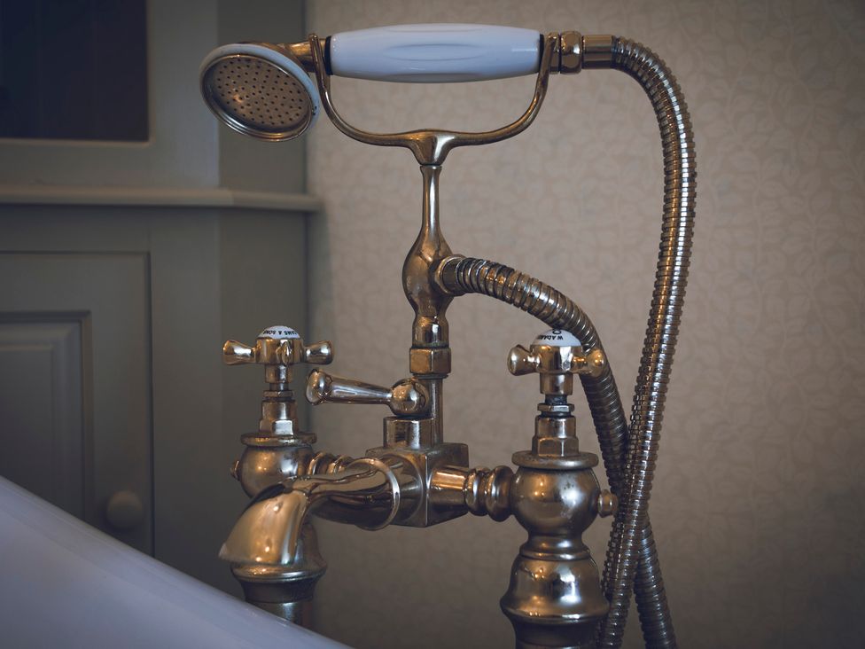 A bath tap with a shower head and controls at Three Mile House in Carnforth