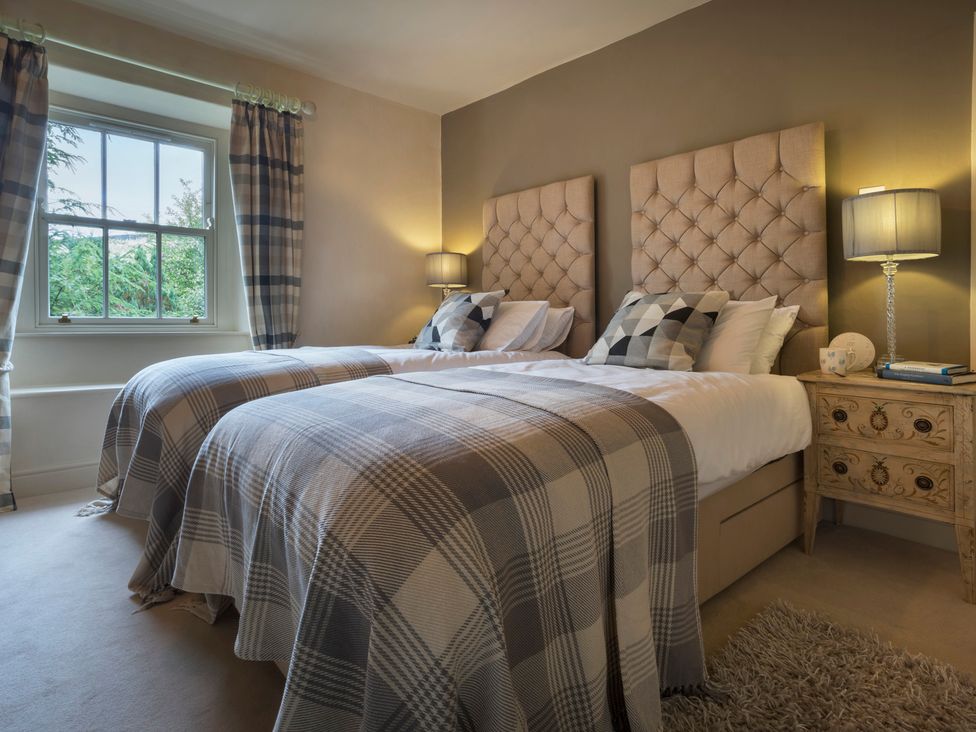 A bedroom with two beds and a bedside table at Three Mile House in Carnforth