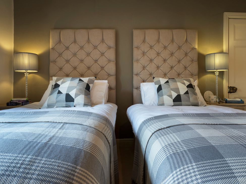 A bedroom with two beds and bedside lamps at Three Mile House in Carnforth
