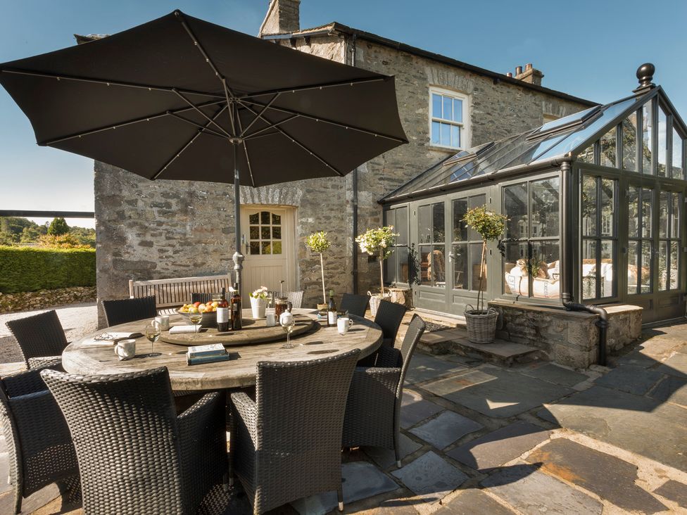 An outdoor dining area with a round table and chairs at Three Mile House in Carnforth