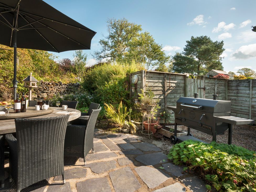 A garden with a table, chairs and a grill at Three Mile House in Carnforth