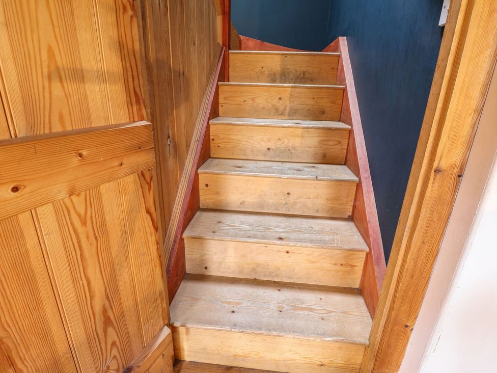 A staircase with wooden steps and a wooden handrail at Llys Gwaun in Fishguard