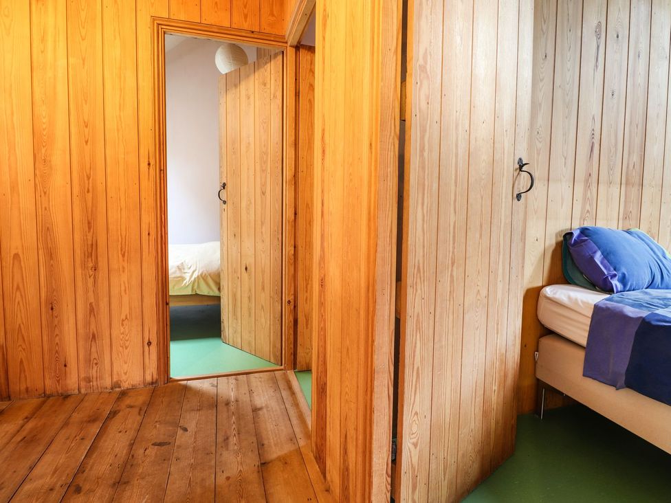 A bedroom with wooden walls and beds at Llys Gwaun in Fishguard