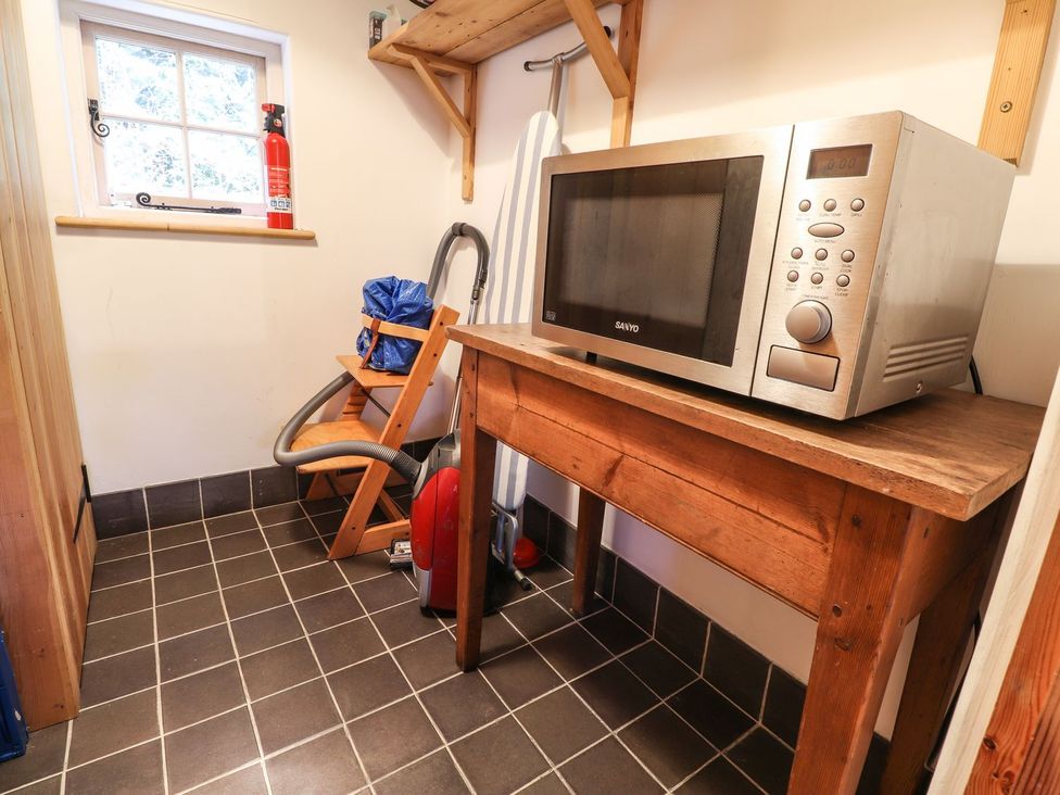 A laundry room with a microwave and vacuum cleaner at Llys Gwaun in Fishguard