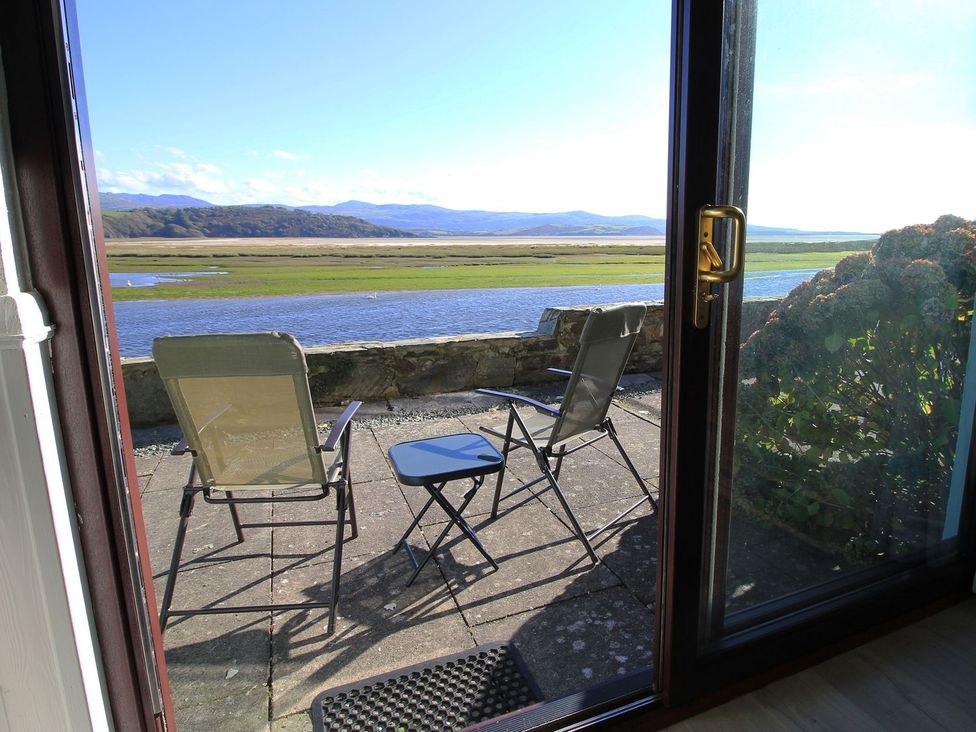 An outdoor seating area with chairs and a table overlooking the water at Aldena South Snowdon Wharf Porthmadog