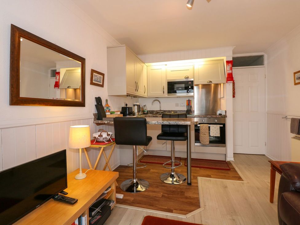 A kitchen with bar stools and appliances at Aldena South Snowdon Wharf Porthmadog