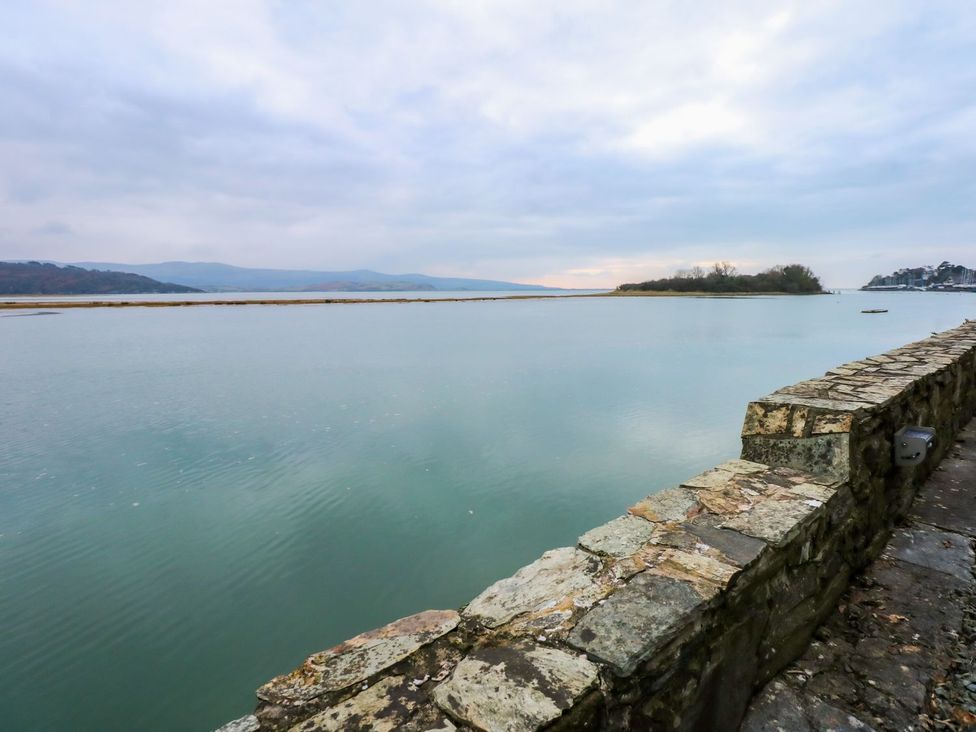 A view of water and a stone wall with an island in the distance at Aldena South Snowdon Wharf Porthmadog