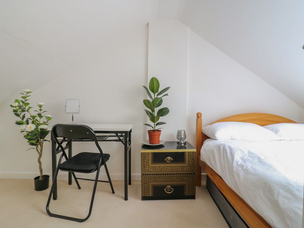 A bedroom with a bed, desk, chair and plants at 2B Granville Road Colchester