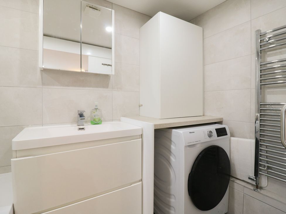 A laundry room with a washing machine and sink at 2B Granville Road Colchester