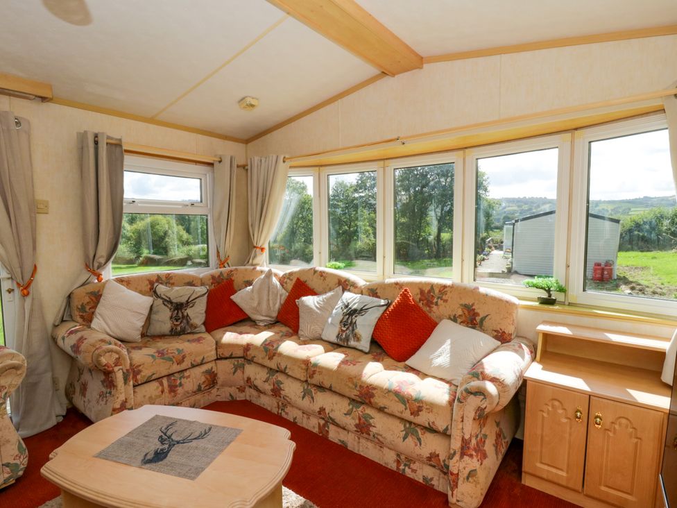 A living room with a floral sofa and large windows at Leven in Lampeter