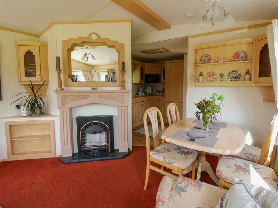 A dining room with a fireplace and table at Leven in Lampeter