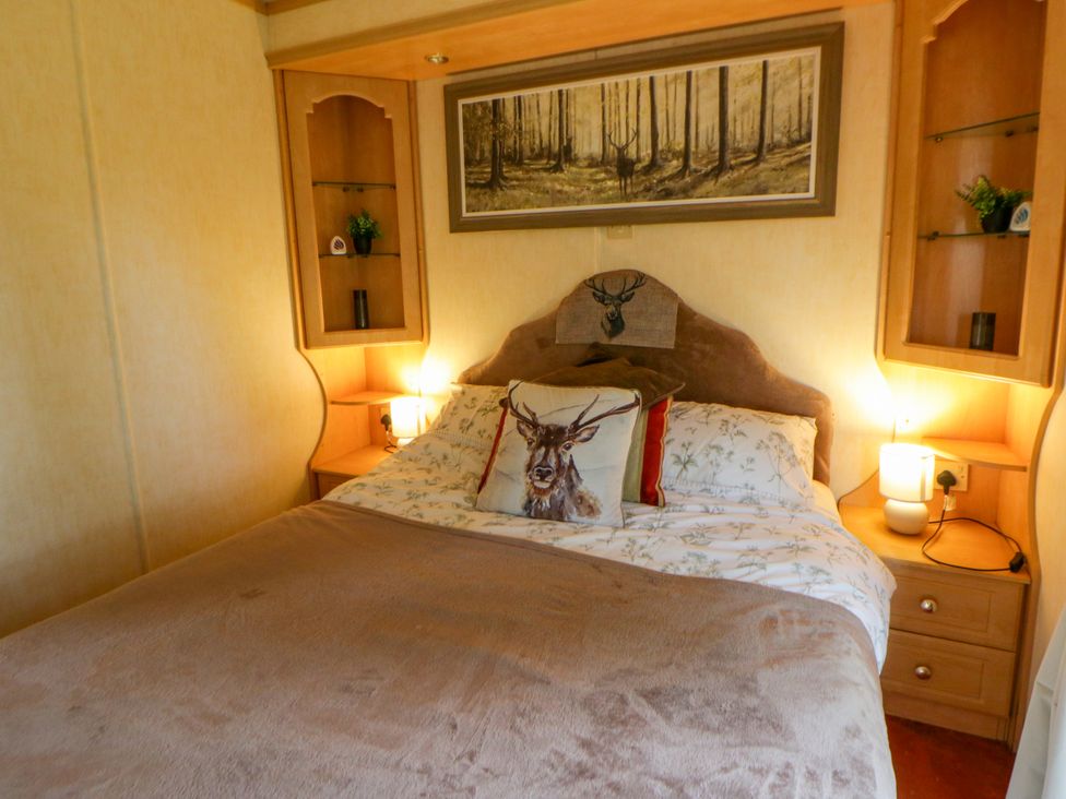A bedroom with a bed and walls shelves at Leven in Lampeter