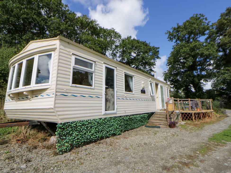 A caravan with a deck and surrounding trees at Leven Lampeter
