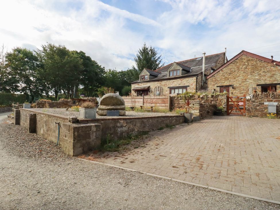An outdoor area with a house, stone wall, garden, and gravel driveway at Skylark in Liskeard