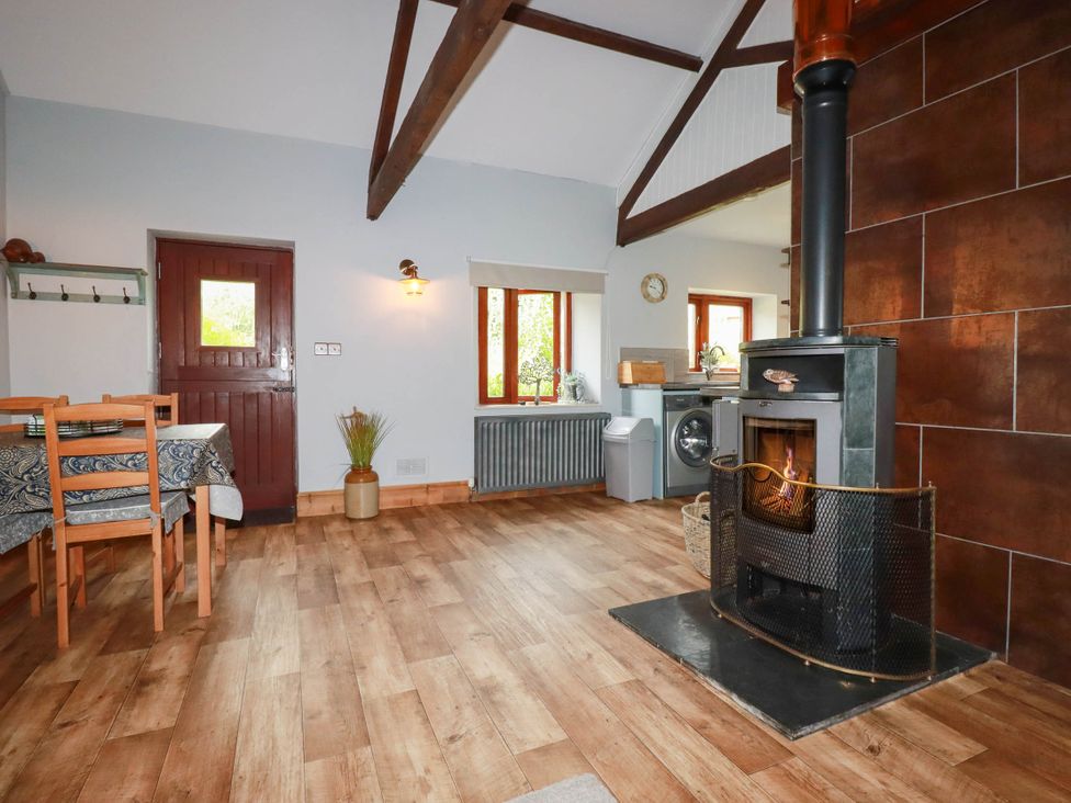 A dining room with a wood stove and a table at Skylark in Liskeard