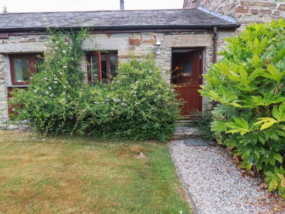 An exterior view of a door surrounded by bushes and a gravel path at Skylark in Liskeard