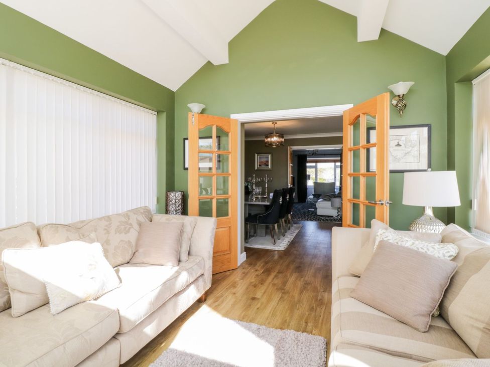 A snug area with a sofa and a view of the dining room at Ger Y Mor in Cemaes Bay