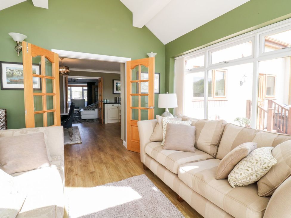 A living room with a sofa and doors at Ger Y Mor in Cemaes Bay